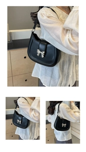 Detailansicht und Styling einer schwarzen Hobo-Tasche mit silberner Schleifenschnalle