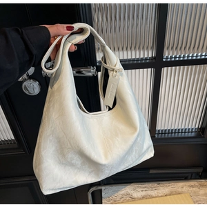 Close-up of beige hobo bag with marble-like texture and branding leather tag
