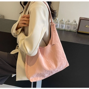 Pink minimalist shoulder bag with unique pleated texture and spacious design worn by a model