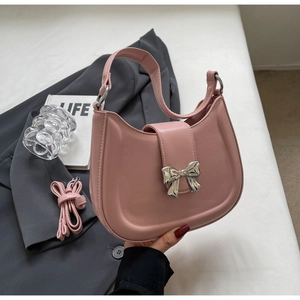 Detail einer rosa Satteltasche mit dekorativem silbernem Bogenverschluss und Lederriemen