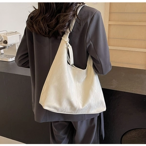 Minimalist cream white shoulder bag shown with side hangtag detail and leather texture