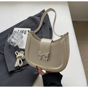 Detail der cremeweißen Tasche mit silberner Schleife und Leder-Schultergurt