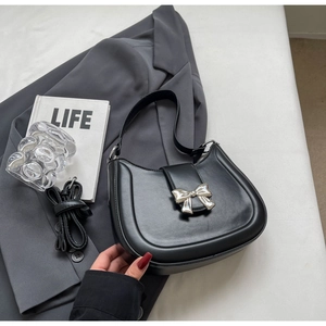 Detail einer schwarzen Satteltasche aus Leder mit silberner Schleife und zwei Trageriemen