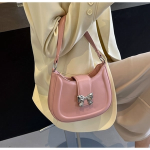 Detail der rosa Umhängetasche mit silberner Schleife getragen zu einem beigen Blazer