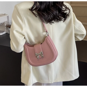 Detailaufnahme einer rosa Ledertasche mit eleganter silberner Metallschleife und Klappe