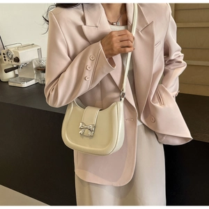 Detail der cremefarbenen Halbmond-Tasche mit silberner Schleife zum eleganten Outfit
