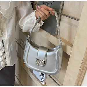 Detail der silbernen Mondsichel-Tasche aus strukturiertem Leder mit Schleifen-Dekor