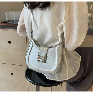 Nahaufnahme einer silbernen Halbmondtasche mit metallischer Schleife und schicker Kette