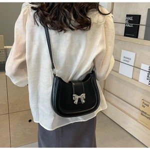 Detail einer schwarzen Leder-Satteltasche mit silberner Schleife als Schultertasche
