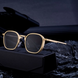 Lunettes de soleil vintage dorées à monture carrée sur un étui en cuir tressé