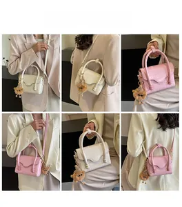 Detail showing crocodile pattern handbag in cream and pink with cute bear charm decoration