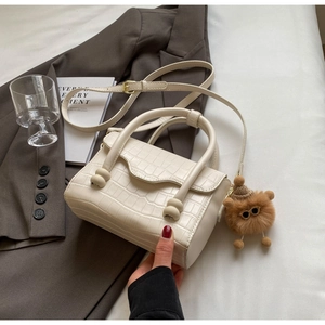 Detail of cream stone pattern crossbody bag with round hardware and plush charm