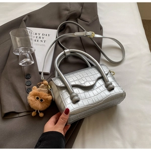 Detail of silver crocodile pattern crossbody bag with cute plush bear charm accessory