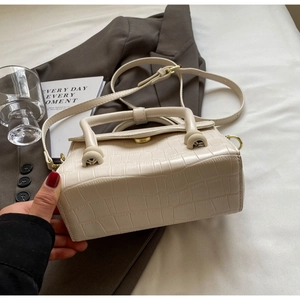 Detail of cream stone pattern handbag with gold hardware and stylish top handle design