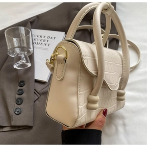 Detail of stone-patterned off-white handbag with gold metal clasp and round handle