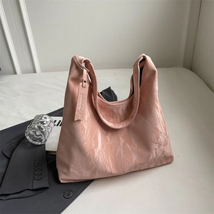 Pink glossy wrinkled Hobo shoulder bag displayed elegantly on a dark grey blazer