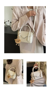Detail of cream stone texture crossbody bag with top handle and plush monster charm