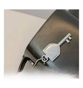 Detail view of silver key-shaped metal hardware on a textured black leather handbag