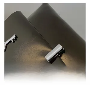 Detail of silver metal padlock and key hardware on vintage black glossy leather handbag