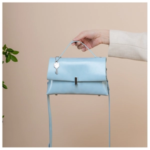 Detail of light blue vintage crossbody bag featuring silver hardware and a key charm accessory