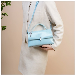 Close-up of light blue leather bag with silver buckle and decorative key charm