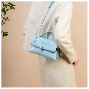 Detail of light blue leather bag featuring a silver lock and a decorative key-shaped charm