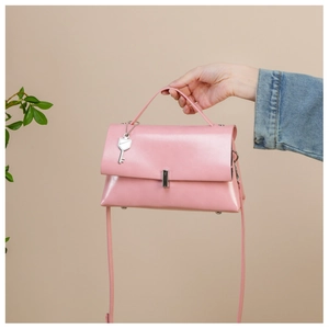 Pink faux leather crossbody bag detail featuring a silver key pendant and metal clasp
