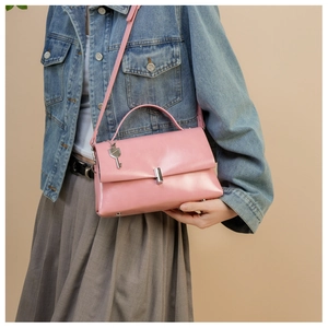 Detail view of pink leather handbag with silver lock and key pendant on a model