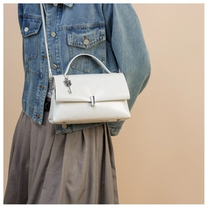 White leather shoulder bag with silver hardware and key charm shown with an outfit