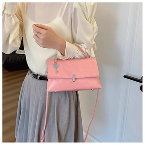 Close-up of pink faux leather crossbody bag featuring silver lock and key charm detail