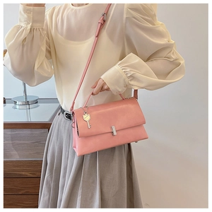 Detail view of pink oil-wax leather shoulder bag with key pendant and silver buckle