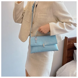 Detail of light blue rectangle crossbody bag with silver key pendant and metal buckle