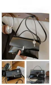 Detail view of black vintage leather shoulder bag with decorative silver key charm