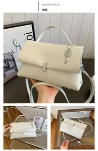 Detail of cream white faux leather handbag featuring metal lock and key charm detail