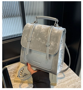 Close-up of silver-gray metallic texture bag with Fashion & Bags logo on marble surface