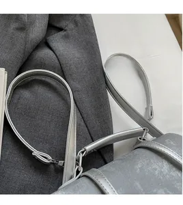 Detail view of smooth long shoulder strap and silver metal hardware on a grey bag