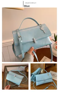 Detail of blue faux leather handbag with silver key charm and adjustable shoulder strap