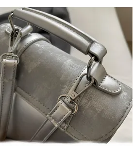 Detail of silver metallic textured handbag showing hardware spring clips and thick handle