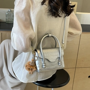 Silver stone pattern shoulder bag with metallic handle and plush charm on a model