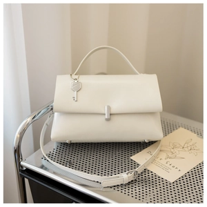 Detail of cream leather handbag with silver key charm and metallic clasp on a cart