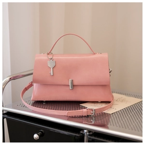 Detail of pink faux leather bag with silver buckle and key-shaped metal pendant charm