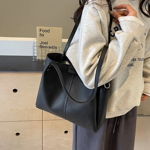 Large black pebbled leather tote bag with wide shoulder strap shown on model