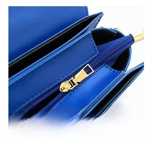 Detail view of royal blue leather handbag featuring gold zipper and multi-layer interior compartments