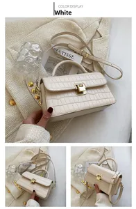 Close-up of white crocodile pattern leather handbag with gold buckle and top handle
