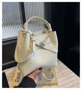 Nahaufnahme der beigen Eimer-Handtasche aus genarbtem Leder mit silbernem Drehverschluss