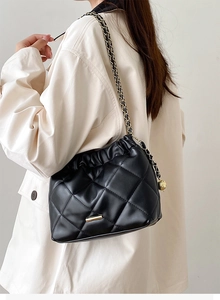 Detail view of black quilted bucket bag with gold chain strap and elegant faux leather texture