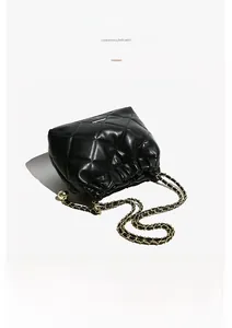 Detail of black quilted leather bucket bag with gold ball metal chain strap