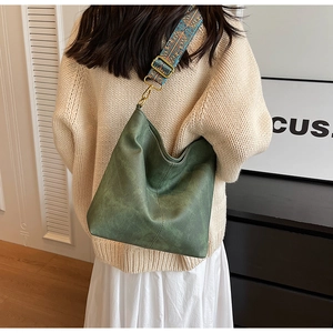 Detail of dark green bucket bag with bohemian embroidered strap on a casual outfit