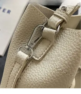 Nahaufnahme der silbernen Karabiner und Premium-Lederstruktur an der Handtasche