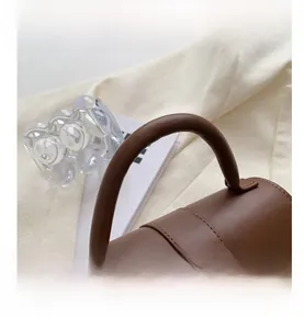 Detail of a dark brown leather handbag handle with precise stitching on white fabric